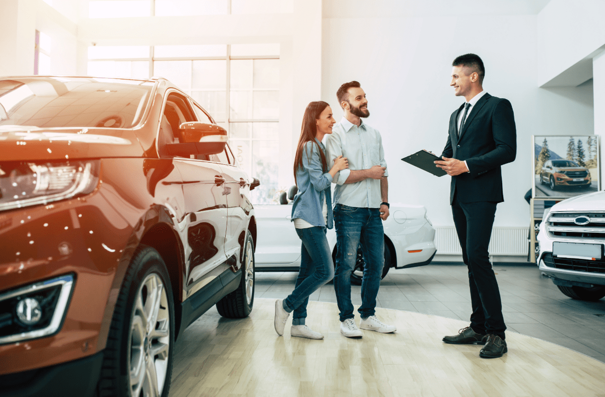 Young couple discussing a new car purchase with cars salesman,