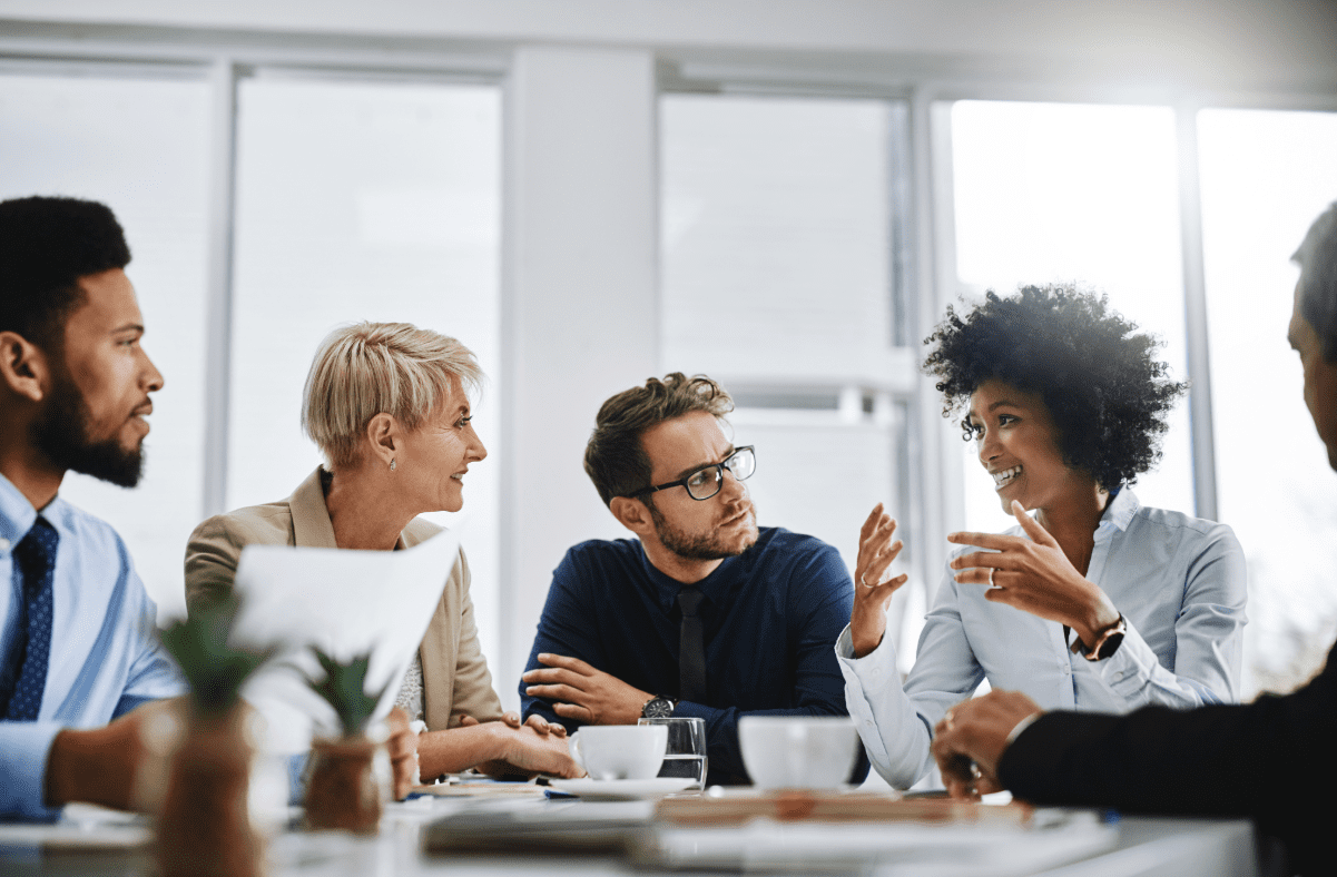 Business meeting with 5 people sitting around a table discussing professional liability insurance