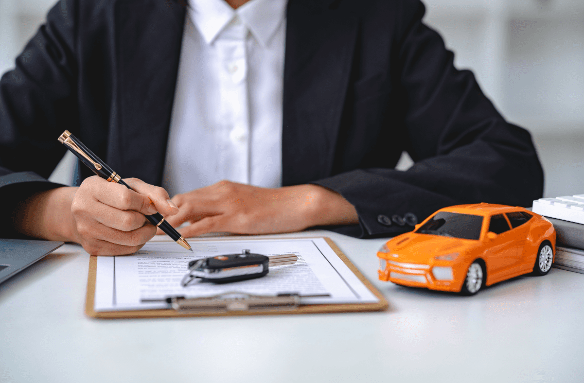 Insurance agent reviewing auto insurance application on clipboard with toy car and car keys on the desk.