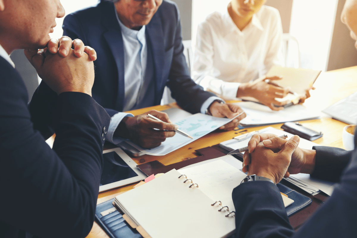 Business executives sitting around table reviewing insurance documents