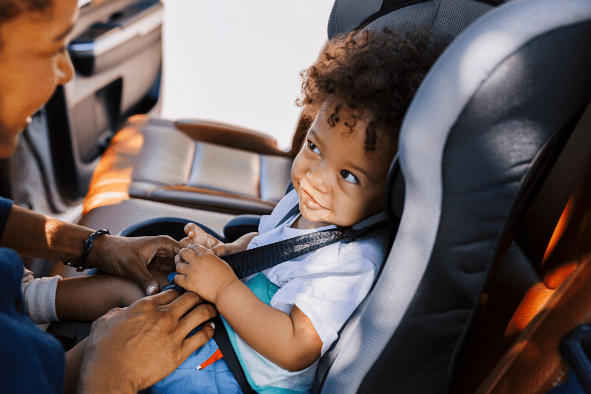 Little boy being buckled into car seat