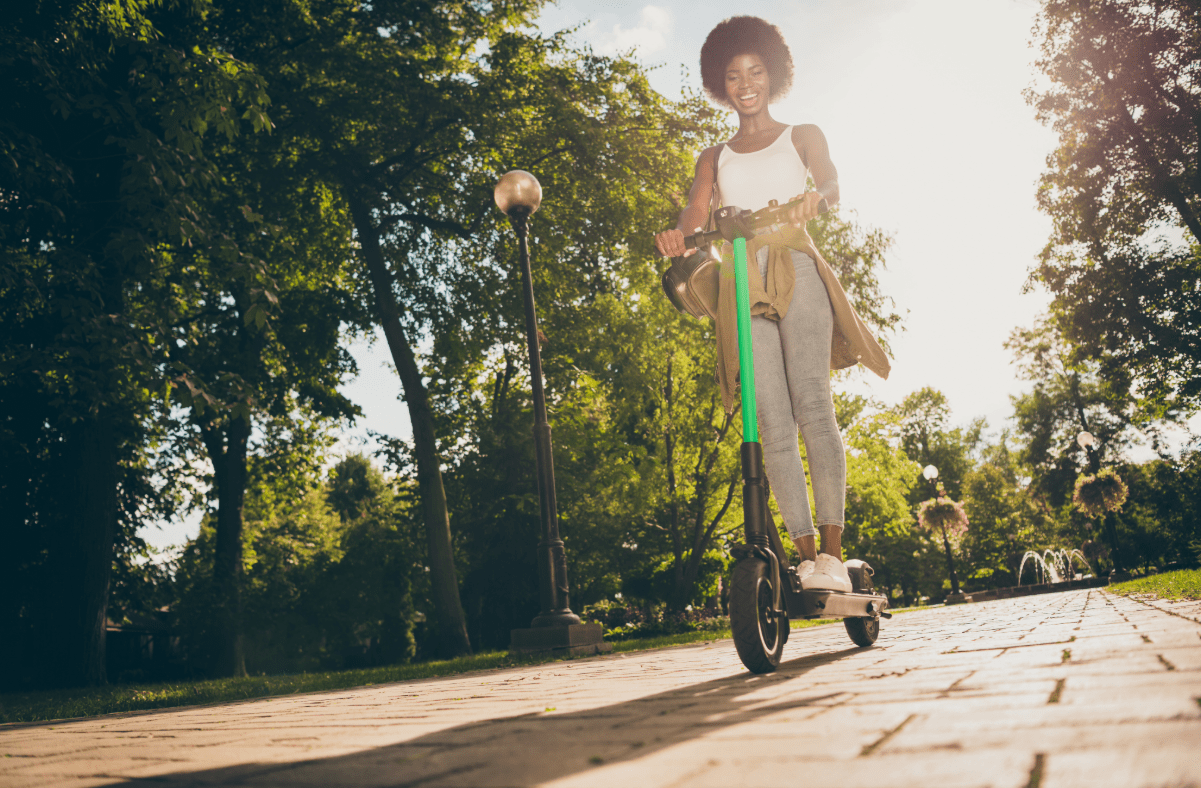 Woman riding rental scooter in park.