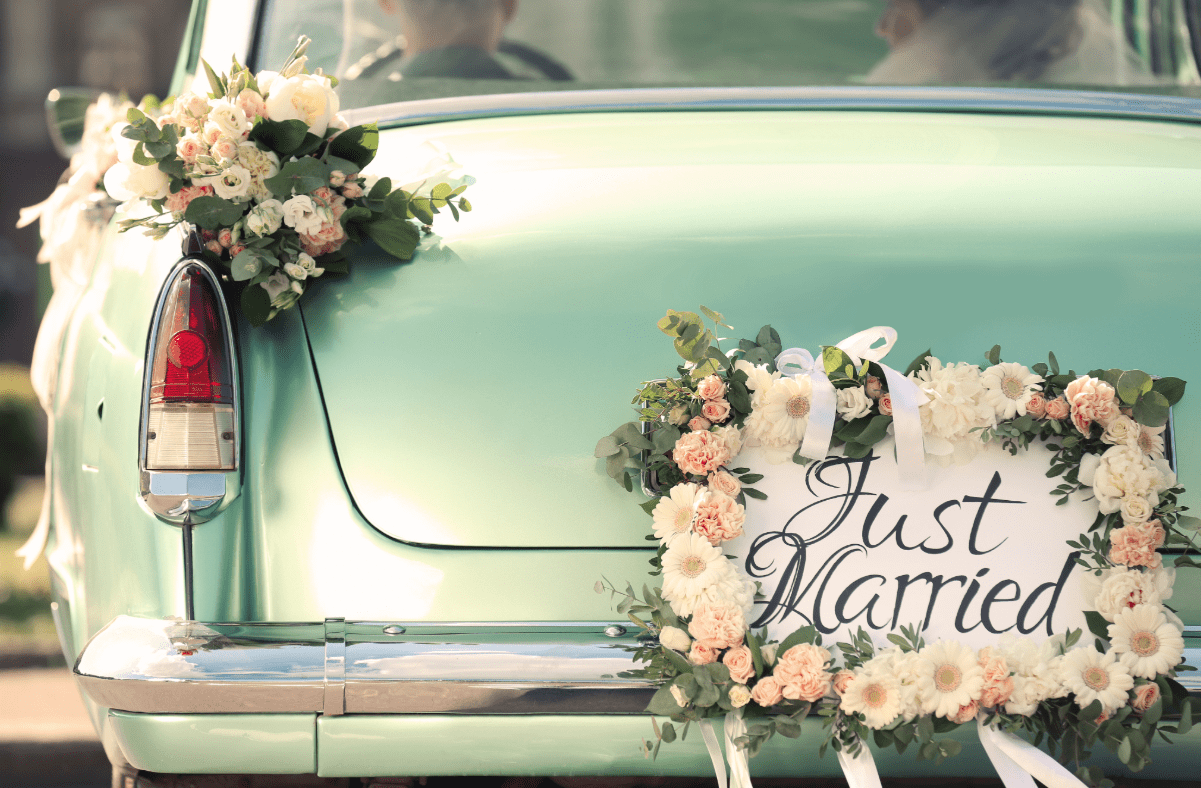 Just married sign on the back of a classic car with flowes