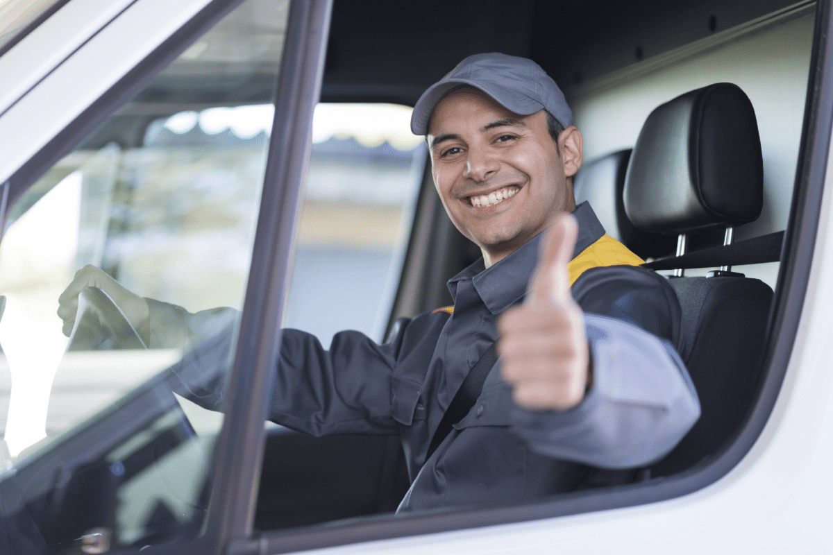 Man sitting in delivery van's driver seat giving a thumbs up.