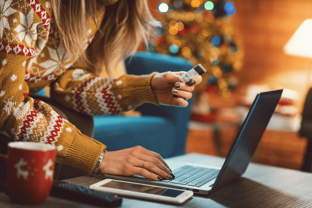 Woman entering credit card information on a computer with holiday decor in the background