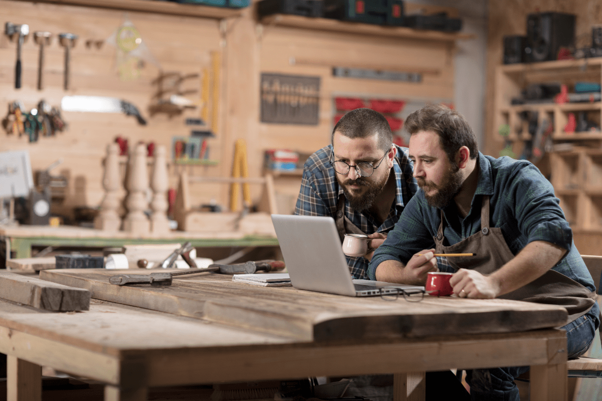 Small business owners review business information on their laptop in their workshop.