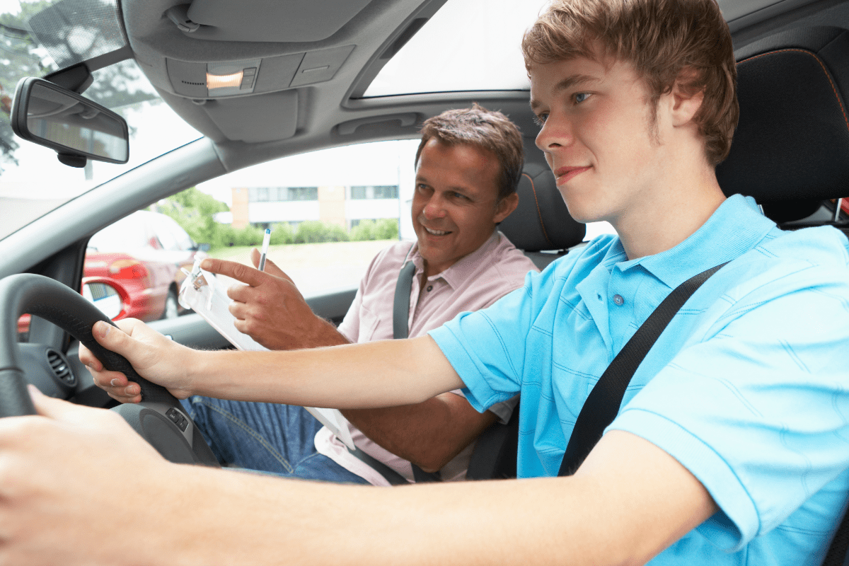 Dad and son in car with dad talking to son about safe driving.